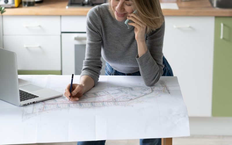 woman-talking-on-cellphone-discusses-the-details-of-an-architectural-project-makes-notes-on-drawing.jpg